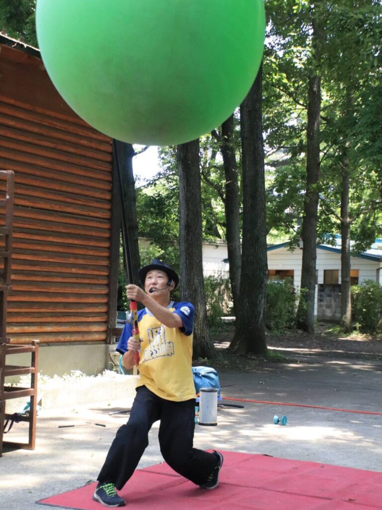 大道芸人GEN（ジェン）が大きな風船を釣り竿につけて投げているパフォーマンスを宇都宮動物園 大道芸イベントで行っている